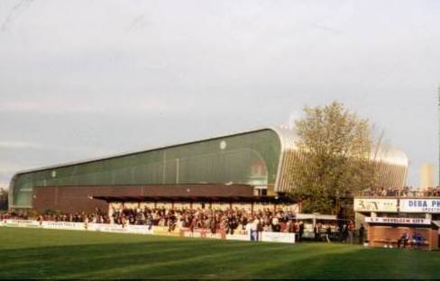 Stadion Wevelgem - Gegenseite, im Hintergrund die benachbarte Sporthalle, rechts einer der gemauerte Trainerbank-Unterst&auml;nde